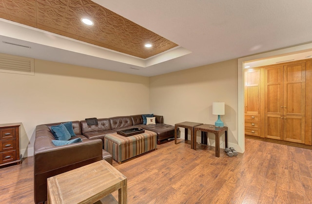 living area with a raised ceiling, wood finished floors, and baseboards