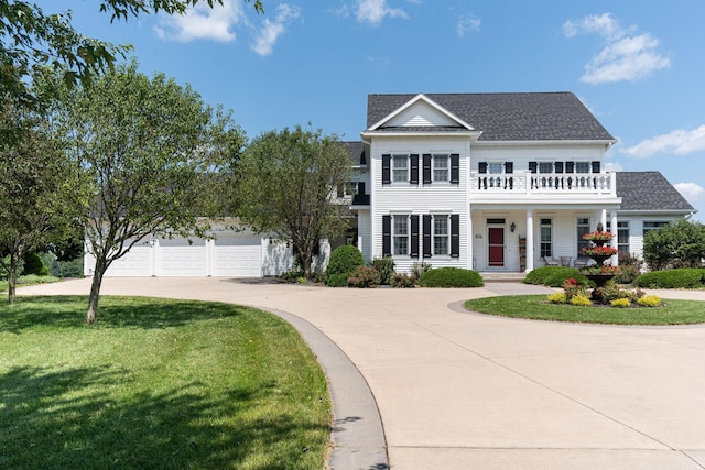 view of front facade with driveway, a front lawn, roof with shingles, and a balcony