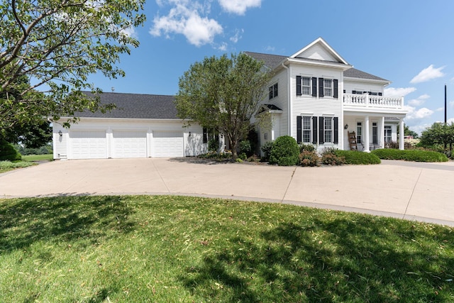 neoclassical / greek revival house with a garage, driveway, a front yard, and a balcony