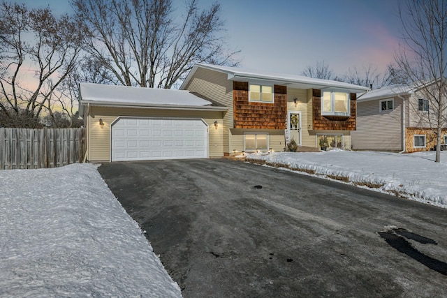 split foyer home with a garage, fence, and aphalt driveway