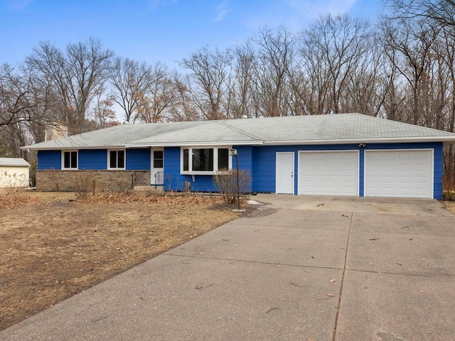 ranch-style house featuring driveway, an attached garage, and a chimney