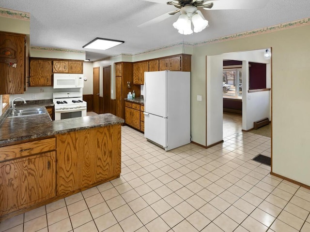 kitchen with a textured ceiling, a peninsula, white appliances, a sink, and dark countertops