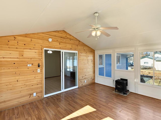 unfurnished sunroom featuring a ceiling fan, lofted ceiling, and a wood stove