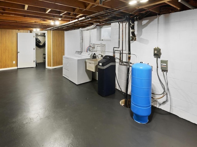 basement featuring concrete block wall, a sink, and washing machine and clothes dryer