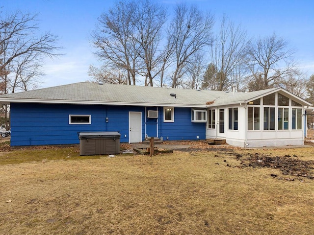 back of property with a wall unit AC, a sunroom, a hot tub, and a yard