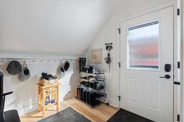 interior space featuring light wood-type flooring, baseboards, and vaulted ceiling