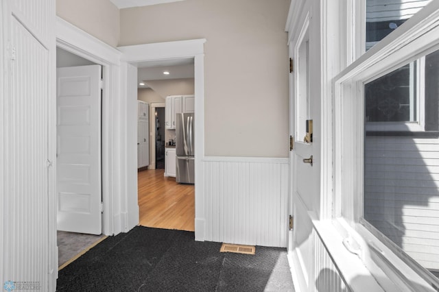 interior space with visible vents, carpet flooring, and wainscoting