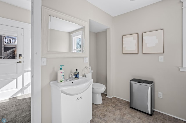 bathroom with toilet, baseboards, and vanity