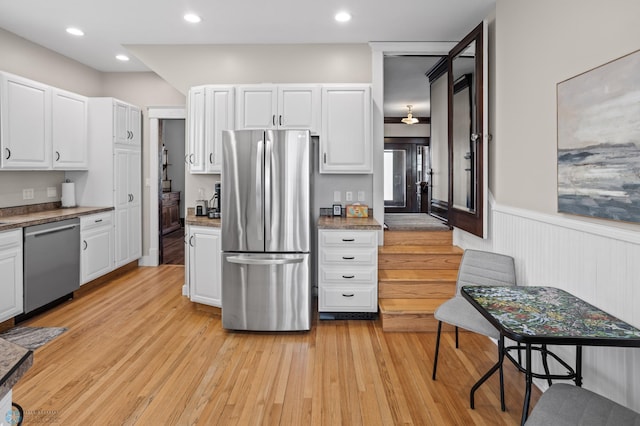 kitchen featuring light wood-style flooring, recessed lighting, a wainscoted wall, stainless steel appliances, and white cabinets