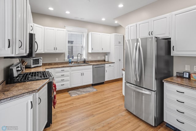 kitchen with appliances with stainless steel finishes, recessed lighting, a sink, and light wood-style flooring