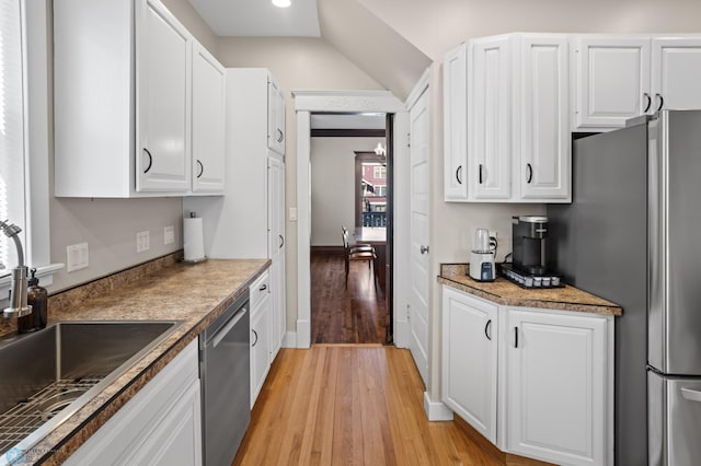 kitchen featuring light wood finished floors, appliances with stainless steel finishes, white cabinets, and a sink