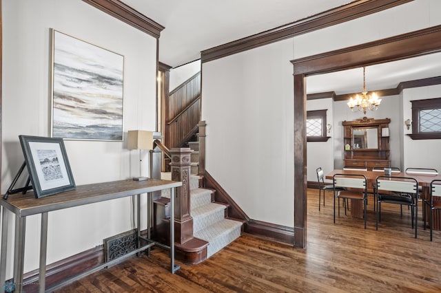 stairs featuring an inviting chandelier, crown molding, and wood finished floors