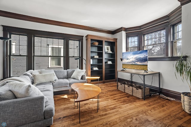 living area featuring baseboards, wood finished floors, and crown molding