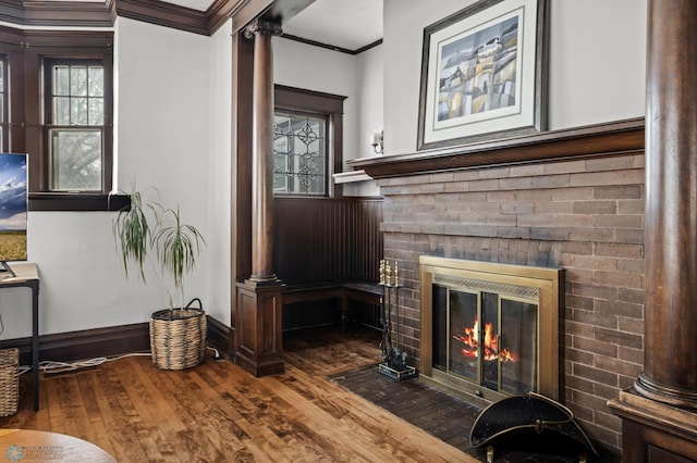 interior space with baseboards, wood-type flooring, ornamental molding, ornate columns, and a fireplace