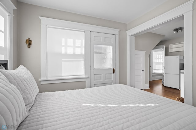 bedroom with freestanding refrigerator and wood finished floors