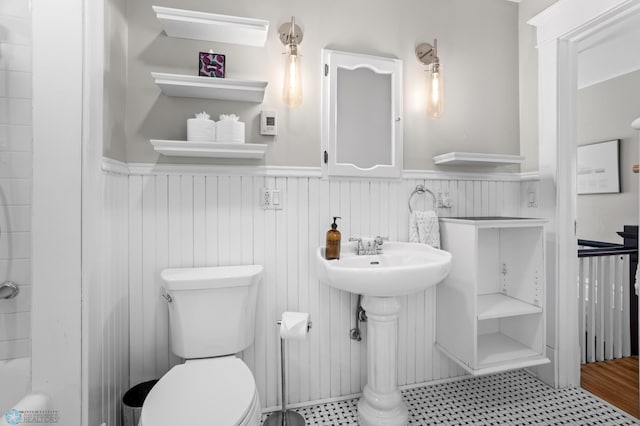 bathroom with a wainscoted wall, a sink, toilet, and walk in shower