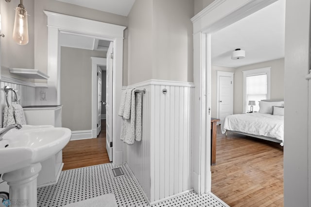 bathroom with visible vents, wainscoting, connected bathroom, a sink, and wood finished floors