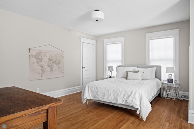 bedroom with a baseboard radiator, baseboards, and hardwood / wood-style floors