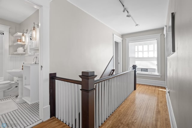 hall with rail lighting, an upstairs landing, and hardwood / wood-style flooring