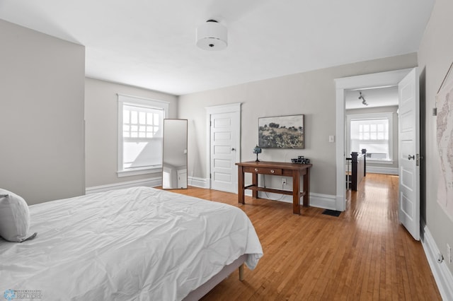 bedroom with multiple windows, baseboards, and wood finished floors