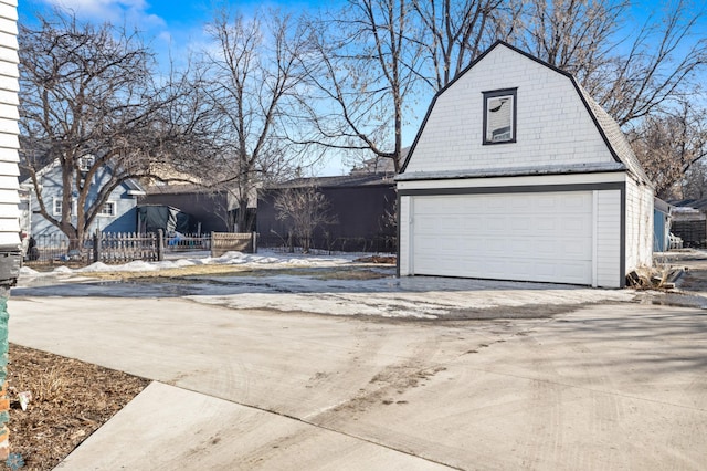 snow covered garage featuring a garage and fence