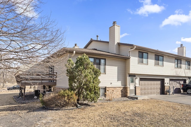 exterior space with a garage, concrete driveway, and a chimney