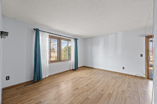 unfurnished room with visible vents, a textured ceiling, baseboards, and wood finished floors