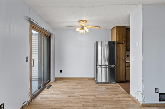 interior space with light wood-style floors, ceiling fan, a textured ceiling, and freestanding refrigerator