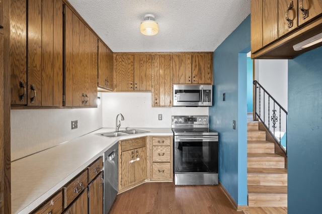 kitchen featuring dark wood finished floors, stainless steel appliances, a textured ceiling, light countertops, and a sink