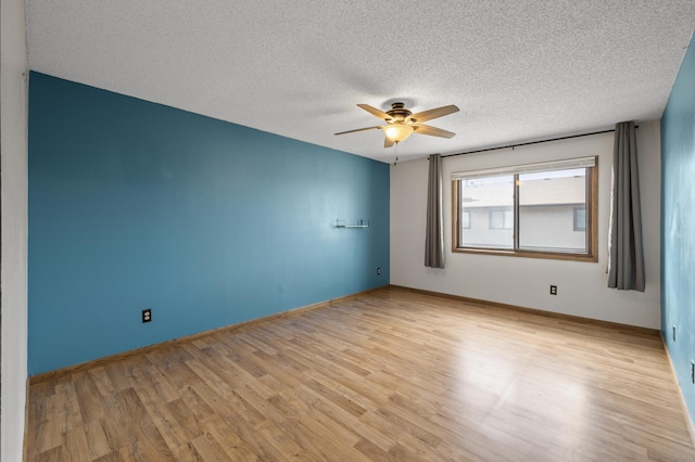 spare room with a textured ceiling, light wood-type flooring, a ceiling fan, and baseboards