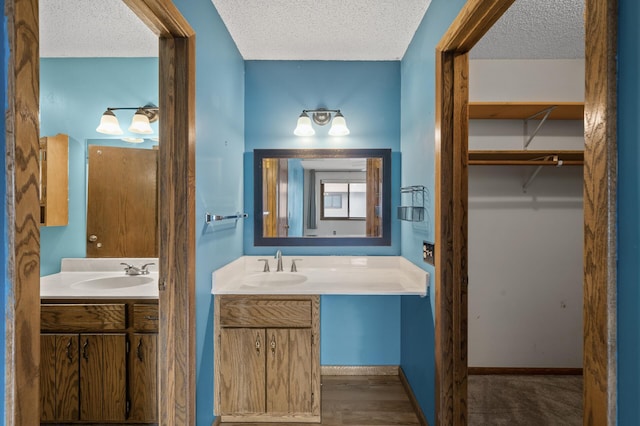 bathroom featuring a walk in closet, vanity, and a textured ceiling