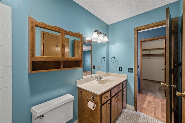 bathroom with baseboards, toilet, tile patterned floors, a textured ceiling, and vanity