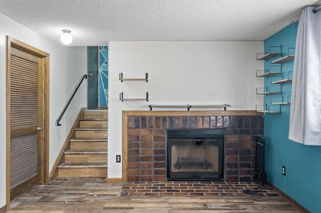 unfurnished living room featuring stairway, a brick fireplace, wood finished floors, and baseboards