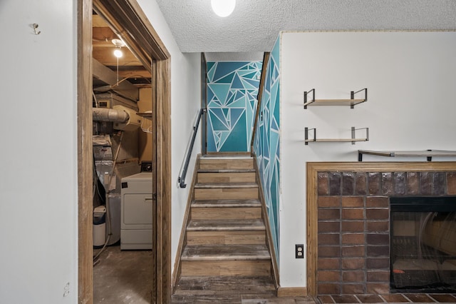 stairway featuring a fireplace, washer / clothes dryer, and a textured ceiling