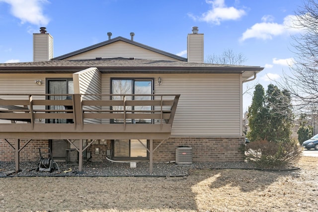 rear view of property featuring cooling unit, a chimney, and a wooden deck