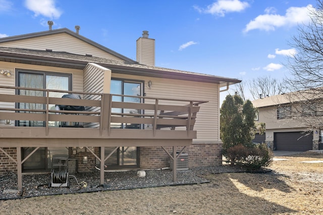 back of property with a garage, brick siding, and a chimney