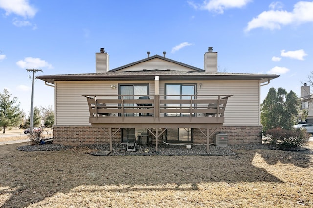 rear view of house featuring brick siding, a chimney, a wooden deck, and central air condition unit