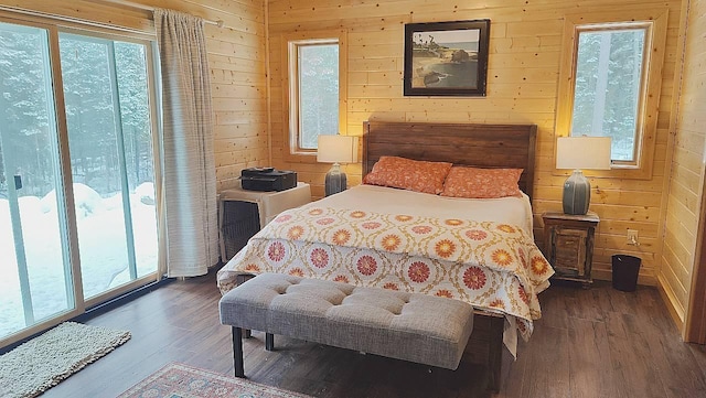 bedroom with multiple windows, wood walls, and wood finished floors