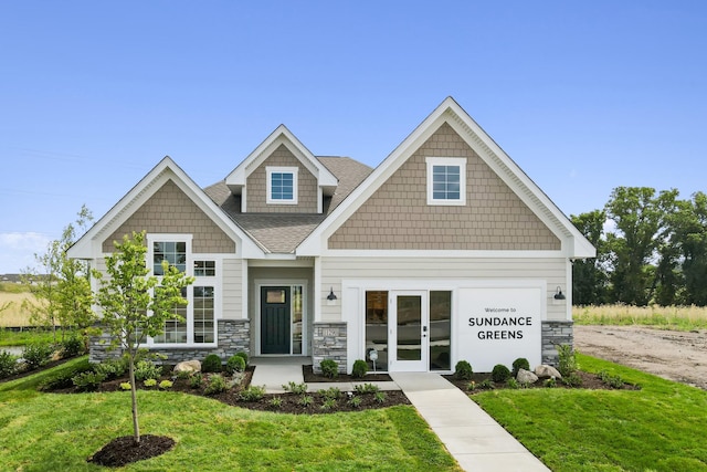 craftsman house with stone siding, a front lawn, roof with shingles, and french doors