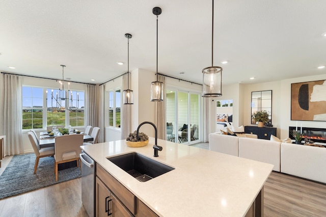 kitchen with a sink, open floor plan, light countertops, dishwasher, and light wood finished floors