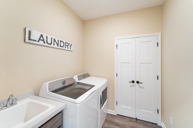 laundry area featuring dark wood-style flooring, washing machine and clothes dryer, a sink, laundry area, and baseboards