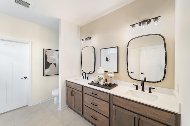 full bathroom featuring toilet, double vanity, a sink, and visible vents