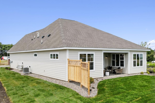 back of house with a shingled roof, central AC, and a lawn