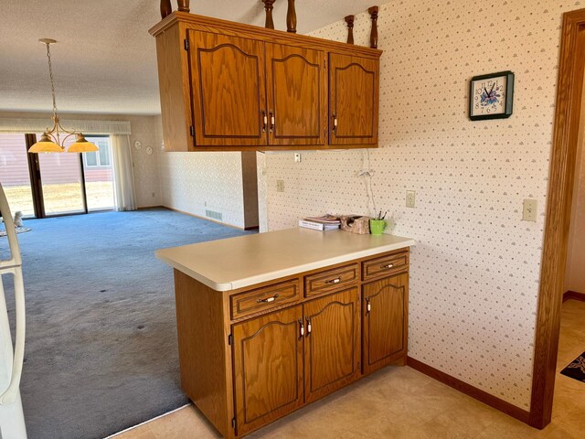 kitchen with wallpapered walls, brown cabinets, light countertops, and light colored carpet