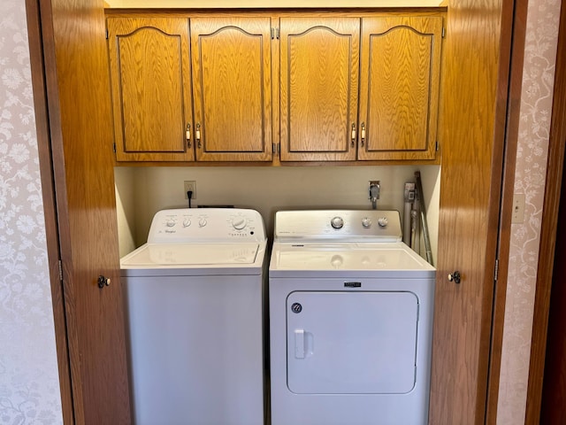 laundry area featuring wallpapered walls, cabinet space, and washer and dryer