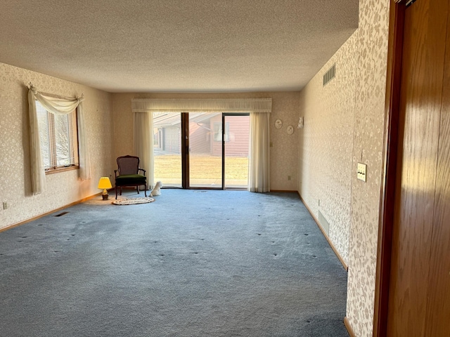 interior space featuring visible vents, a textured ceiling, and wallpapered walls