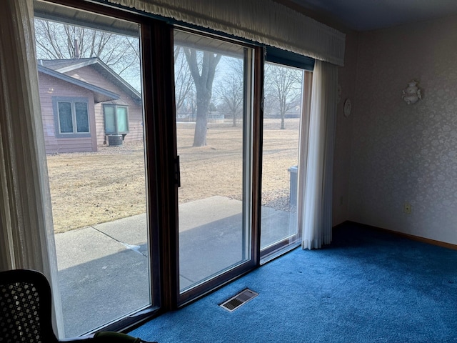 doorway with carpet floors, visible vents, and baseboards