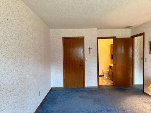 unfurnished bedroom featuring a textured ceiling, carpet flooring, and wallpapered walls