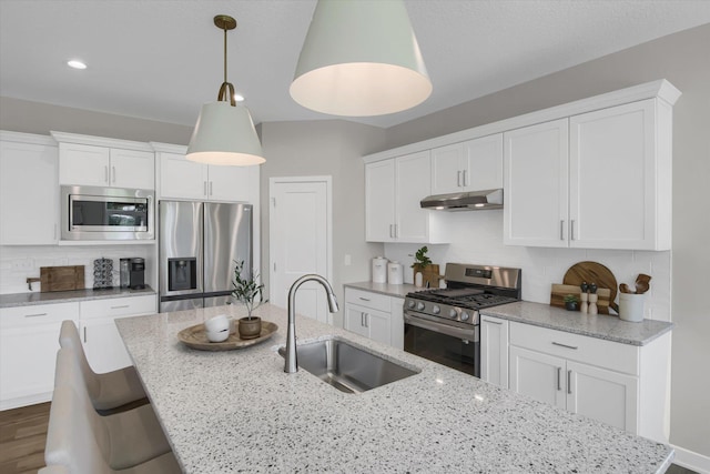 kitchen featuring decorative backsplash, appliances with stainless steel finishes, white cabinets, a sink, and under cabinet range hood