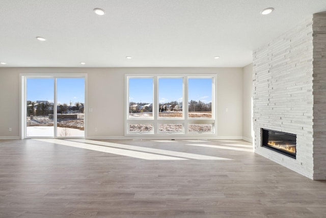 unfurnished living room featuring recessed lighting, a fireplace, wood finished floors, and baseboards